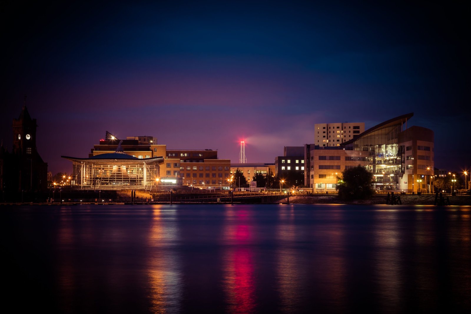 Home Stunning view of Cardiff Bay's illuminated skyline at night reflecting on the water.