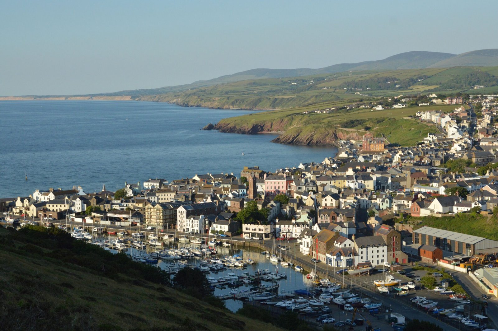 Home A picturesque view of Peel marina and town on the Isle of Man, showcasing the coastline.