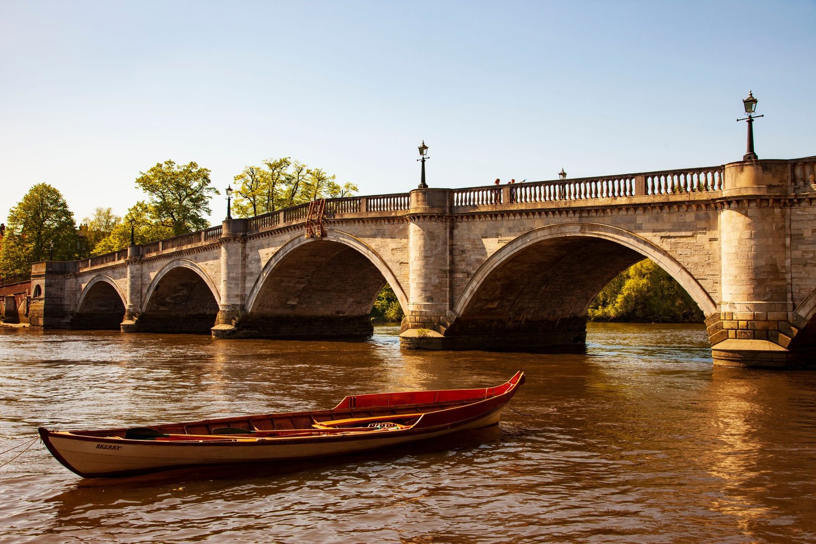Home Richmond Bridge in England with a boat on the River Thames. A peaceful, sunny day captures this iconic landmark.